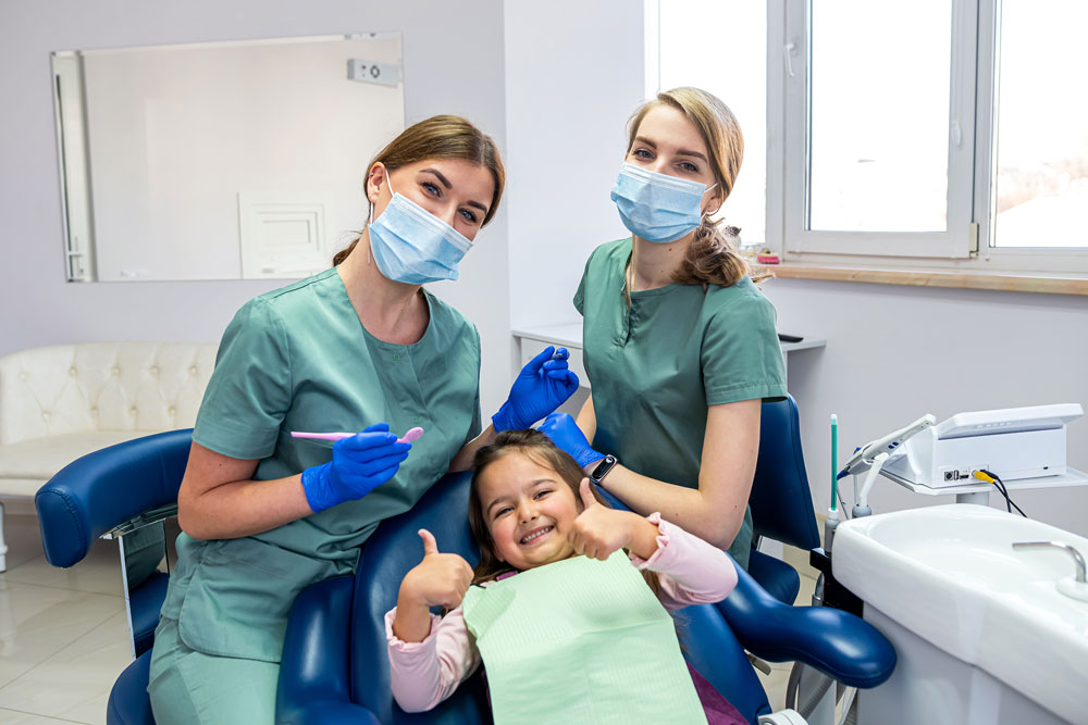 Dental assistants smiling with little girl patient